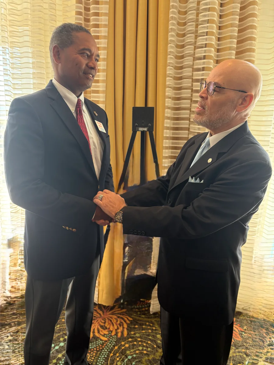 Victor Arias shakes hands with another man during an indoor gathering.